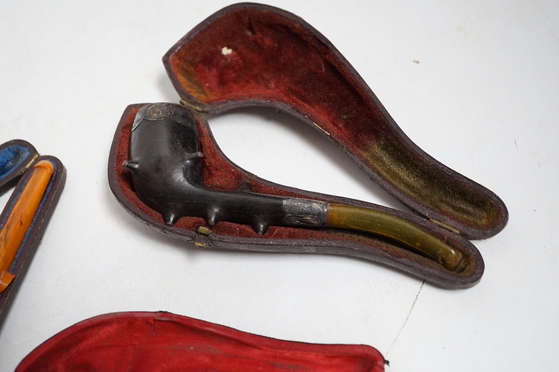 Three cased pipes, one with carved amber novelty bowl, the other two with amber pipe ends, metal mounted, together with a tortoiseshell and mother of pearl card case, Card case 10.5cm high x 8cm wide